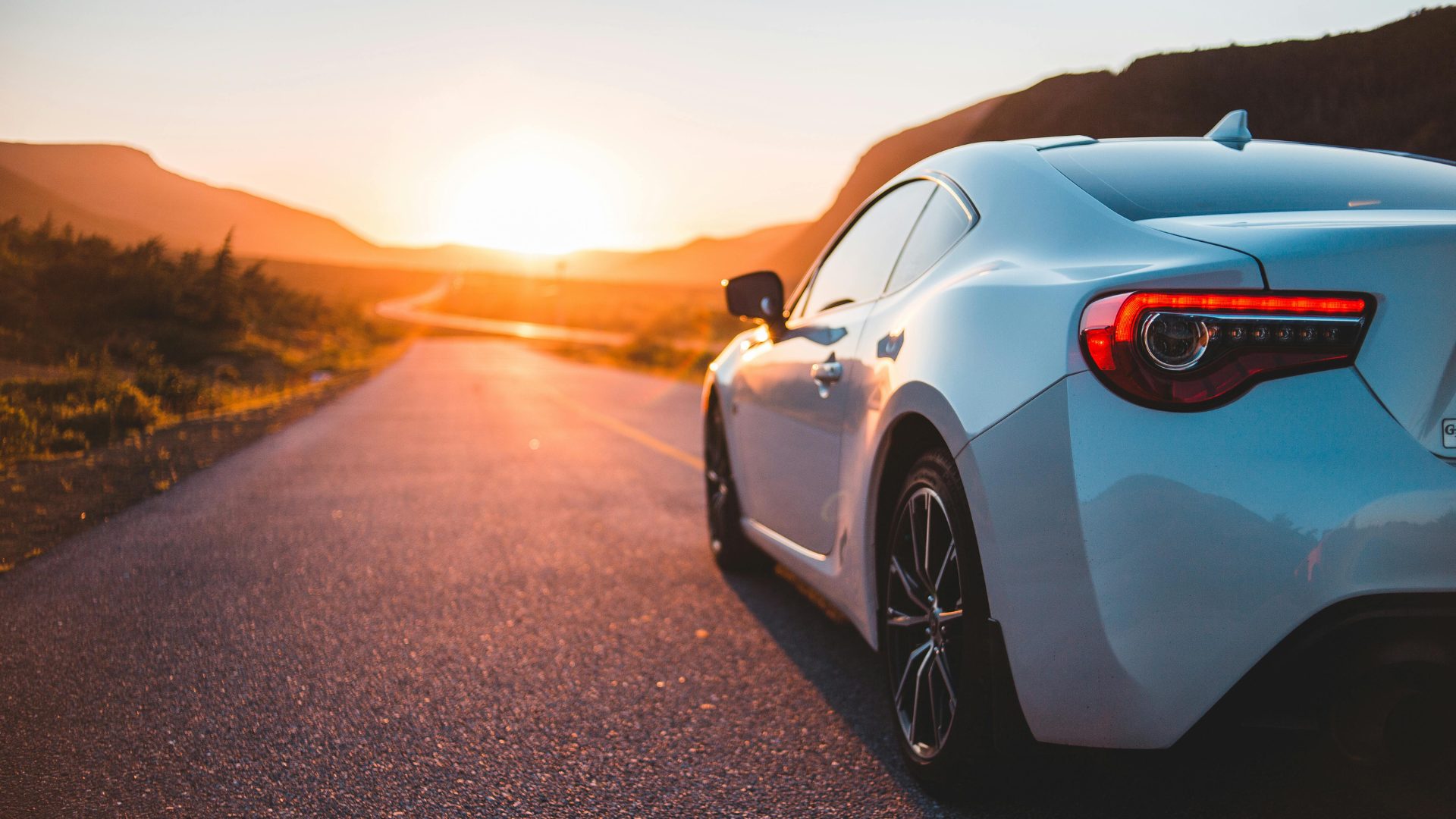 Car on an open New Zealand road at sunset