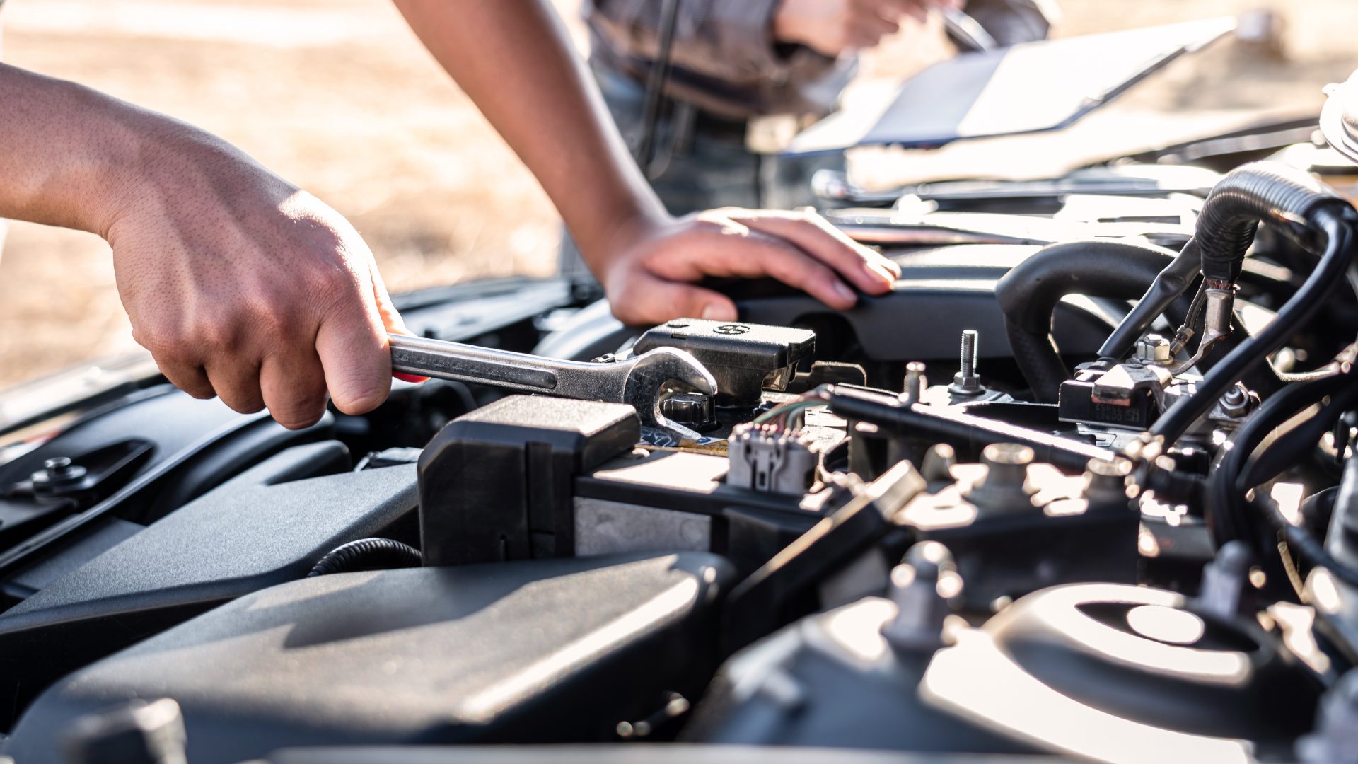 Mechanic working under the bonnet of a car with a wrench